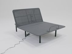 a gray bed frame with an electric plugged in to the side and wires running through it