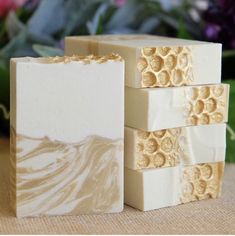 three soap bars stacked on top of each other with flowers in the backgroud