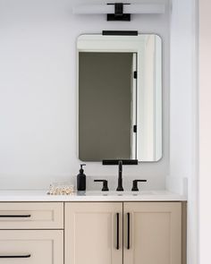 a bathroom vanity with two sinks and a large mirror above it, in front of a white wall