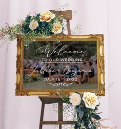 a wedding welcome sign with flowers and greenery