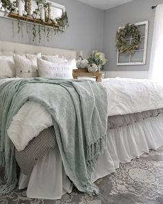 a white bed sitting in a bedroom next to a window with plants on top of it