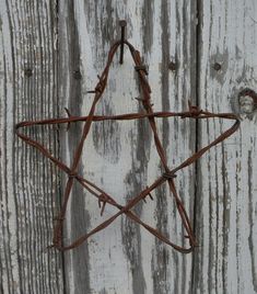 a star made out of barbed wire on a wooden wall with rusted metal bars