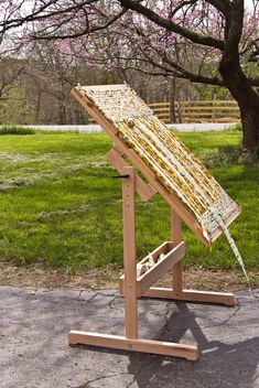 a wooden easel sitting on top of a cement ground next to a green field