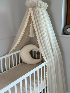 a baby crib with a white canopy over it and a pillow on the bed