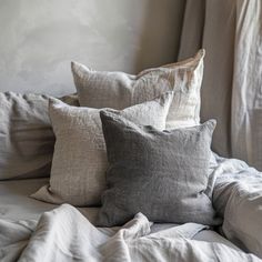 a bed with white sheets and gray pillows