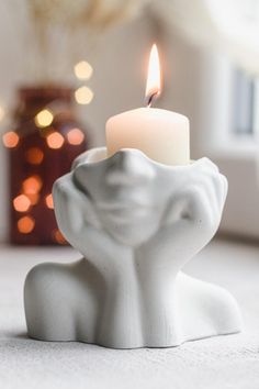 a white candle holder with a lit candle in the shape of an elephant's head