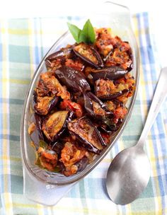 a glass dish filled with cooked eggplant on top of a checkered table cloth