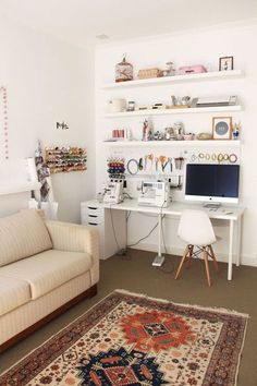 a living room with a couch, desk and computer on the wall next to it