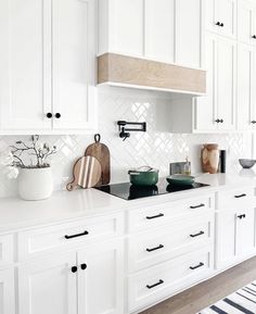 a kitchen with white cabinets and black stove top burner, potted plant on the counter