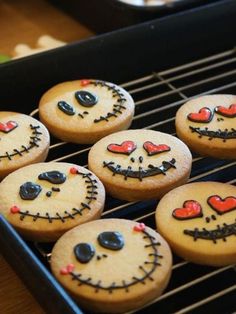 some cookies with faces on them are cooling on a rack in front of other ones