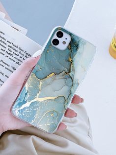 a person holding an iphone case with blue and gold marble