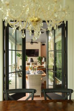 a dining room table with chairs and a chandelier hanging from it's ceiling