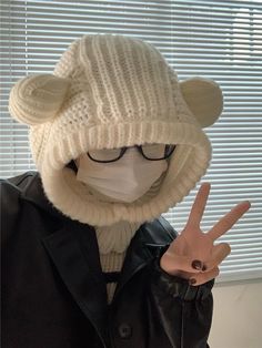 a person wearing a white hat and glasses making the peace sign with their hand in front of them