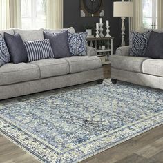 a living room with two couches and a rug in front of the sofas