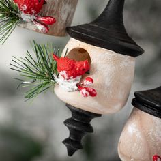 two red birds are perched on top of the birdhouses, decorated with pine needles and snow