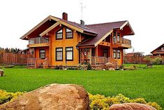 a wooden house sitting on top of a lush green field next to rocks and flowers