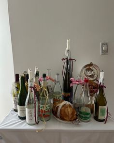 a table topped with lots of bottles of wine next to bread and other food items