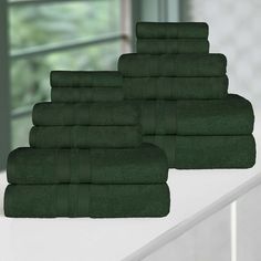 a stack of green towels sitting on top of a white counter