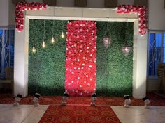 a room decorated with red flowers and greenery for a wedding or special event venue