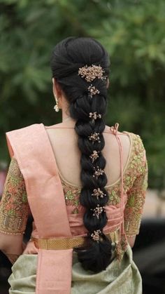 a woman with long black hair wearing a pink sari and braid in her hair