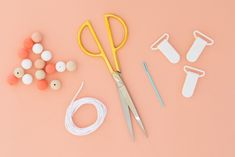 sewing supplies laid out on top of a pink surface with scissors, thread and pins