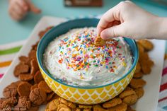 a person dipping some kind of food in a bowl with sprinkles on it