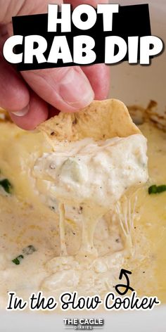 a hand dipping a tortilla chip into a bowl of hot crab dip