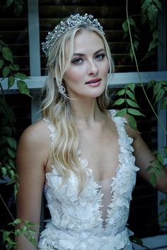 a beautiful blonde woman wearing a white dress and tiara with flowers on her head