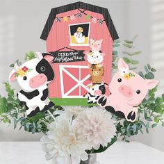 a vase filled with flowers and cutouts of farm animals in front of a barn