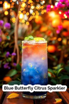 a blue butterfly citrus sparkler cocktail on a wooden table with lights in the background