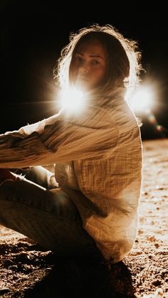 a woman sitting on the ground with her arms crossed and head turned to the side