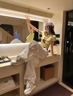 a woman sitting on top of a counter next to a mirror