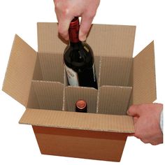 a person opening a wine bottle in a cardboard box