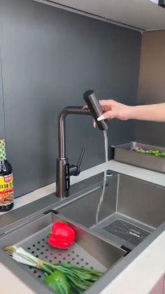 a person is washing vegetables in a kitchen sink with the faucet running down