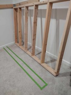 an unfinished room with some green tape on the floor and two wooden frames in front of it