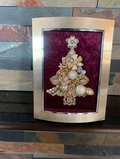 a christmas tree made out of pearls and other jewels in a frame on a mantle