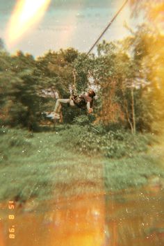 a man riding a zip line over a lush green forest