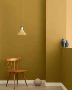 a wooden chair sitting in front of a wall with a light hanging from it's side