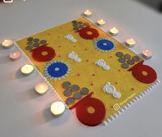 a table topped with lots of candles next to a yellow and red cloth covered in flowers