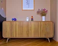 a wooden cabinet with two vases sitting on top of it next to a painting