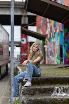 a woman is sitting on some steps in front of a building with graffiti painted on it