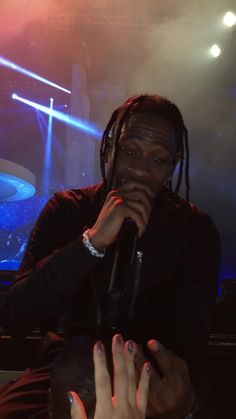 a man with dreadlocks sitting in front of a microphone and holding his hand to his mouth