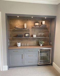 a kitchen with gray cabinets and shelves filled with wine glasses, coffee mugs and other items