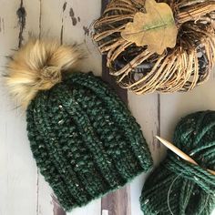 a green knitted hat next to a ball of yarn and a pair of knitting needles