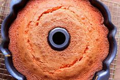 an orange cake in a blue pan on a cooling rack with a black ring around the top