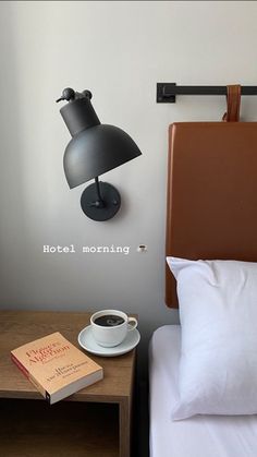 a hotel room with a bed, lamp and coffee cup on the nightstand next to it