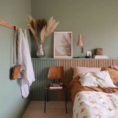 a bed sitting in a bedroom next to a wall with pictures and plants on it