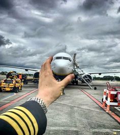 a person taking a photo of an airplane on the tarmac with stormy skies in the background