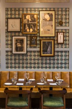 a dining room with tables and chairs in front of a wall with pictures on it