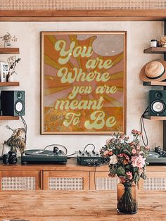 there is a vase with flowers in it on the table next to some records and speakers